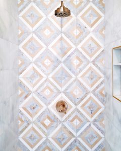 shower wall with brass fixtures and geometric tiles