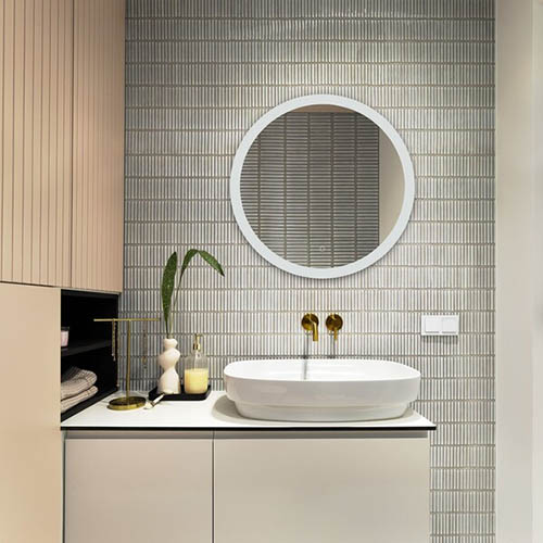 Interior design of elegant bathroom with gold tape, blue tiles, classic white sink, glass soap dispenser, beige wase with green leaves and personal accessories. Home decor. Template.